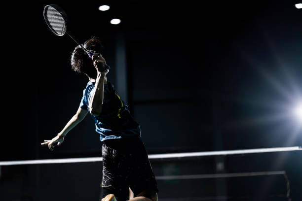 il giocatore di badminton asiatico sta colpendo in tribunale - badminton sport foto e immagini stock