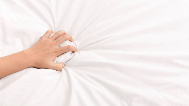 female hand grasping white crumpled bed sheet - orgasm imagens e fotografias de stock