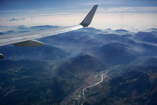 霧の山、都市、川、雲と飛行機の翼、太陽の反対の上空のビュー - mountain range earth sky airplane ストックフォトと画像