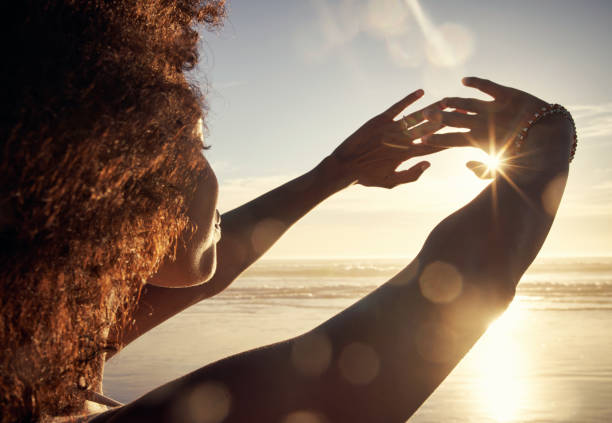 The ocean breeze brings a life of ease Rearview shot of a young woman blocking the sunlight with her hands at the beach woman lifestyle stock pictures, royalty-free photos & images