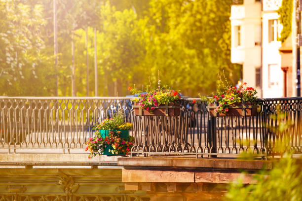 Beautiful spring flowers in the plant pots hanging on the bridge enclosure of Ill river in Strasbourg, France