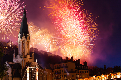 Fireworks lightening the dark sky over the bell tower of Saint Georges church in Lyon, France