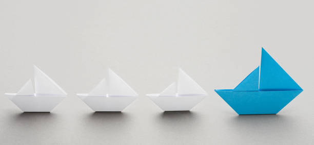 istock Blue paper boat leading white ships, panorama 1133824058
