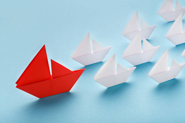 istock Red paper boat leading white ships, panorama 1133824060