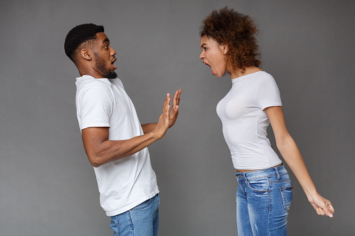 Domestic fight. Angry african-american woman shouting at her man on gray background