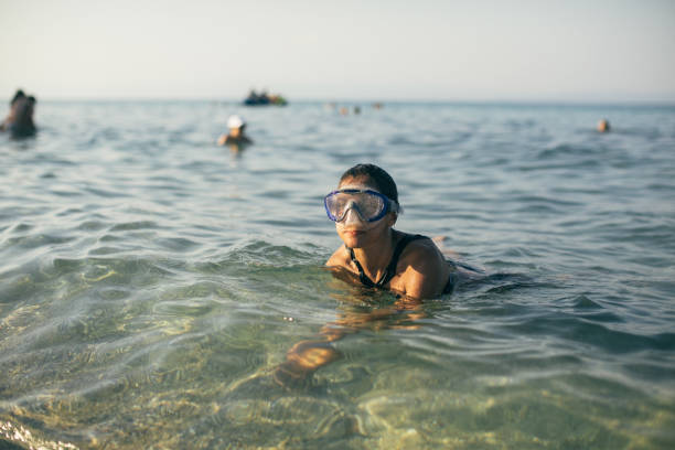 Woman wearing a snorkel scuba mask while swimming in the sea, Greece