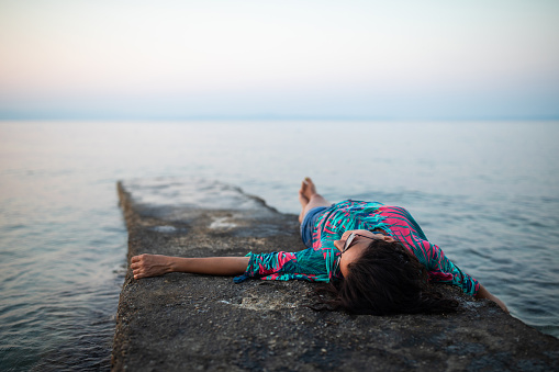Woman lying on the pier,  enjoying by the sea alone, Halkidiki, Greece
