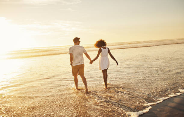Our love is as beautiful as this sunset Shot of a young couple bonding at the beach couple holding hands stock pictures, royalty-free photos & images