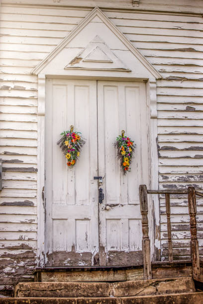 Old, weathered, wooden church doors adorned with spring flower arrangements
