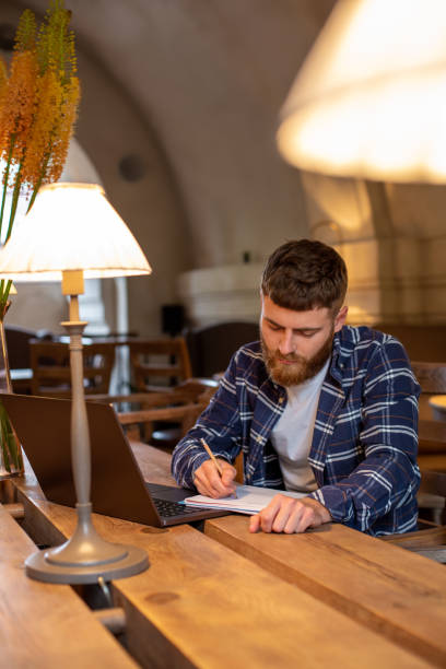 istock Casual business man or freelancer planning his work on notebook, working on laptop computer with smart phone, cup of coffee on table at coffee shop or home office. 1133834317