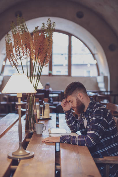istock Young bearded businessman sits in cafe, home at table and writes 1133834401