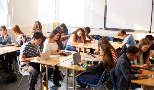 istock Wide Angle View Of High School Students Sitting At Desks In Classroom Using Laptops 1133835378