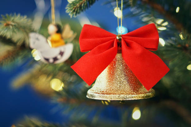 retrato borrado do natal. sino dourado brilhante com uma curva vermelha de veludo em uma árvore de natal. fundo da festão das luzes. fundo básico de bokeh para o projeto - bow christmas red velvet - fotografias e filmes do acervo