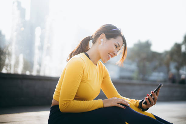 smiling sports woman taking rest and using smartphone after urban work out in the city - self improvement audio imagens e fotografias de stock