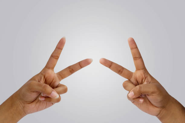 Fingers Showing Peace Or Victory Two Hands Showing the sign of PEACE or VICTORY or STRENGTH symbol and letter V in sign language by raising two fingers up on white background. vendetta stock pictures, royalty-free photos & images