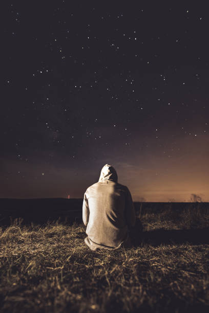 istock Man sitting on the hill against stars on the sky. 1133842828