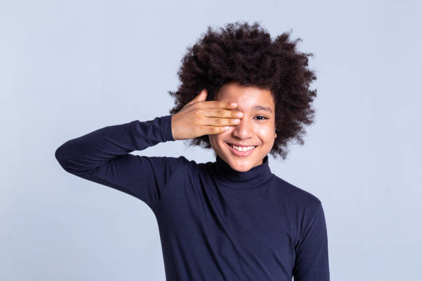 istock Smiling curly positive child closing one eye with hand 1133845499