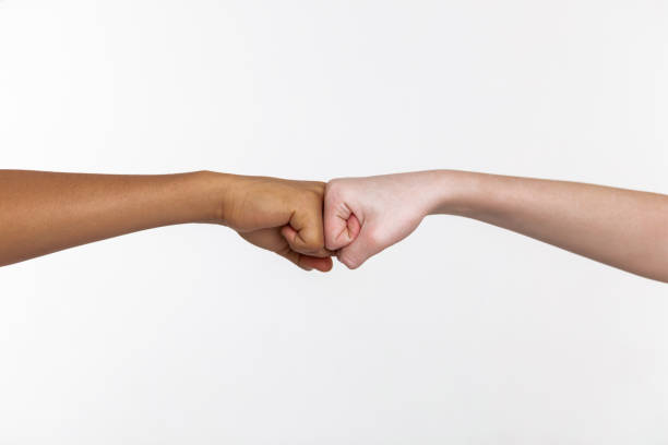 istock Pale and bronzed hands on white background connecting closed fists 1133850756