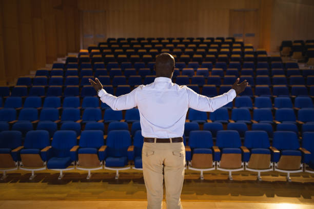 istock Businessman with arm stretched out standing in a auditorium 1133851816
