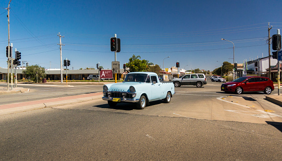 A blue vintage Holden utility vehicle, driving on the road in the city of Broken Hill, New South Wales, Australia