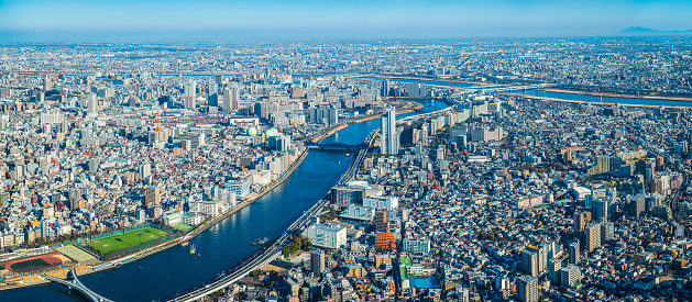 Aerial panoramic view over the rooftops and skyscrapers of Tokyo, along the Sumida River to the Arakawa River beyond, Japan.