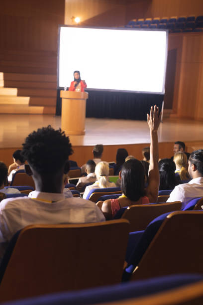 istock Woman sitting in audience raising hand for asking question 1133855312