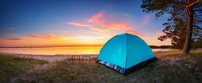 Family resting with tent in nature at sunset. Weekends near seaside