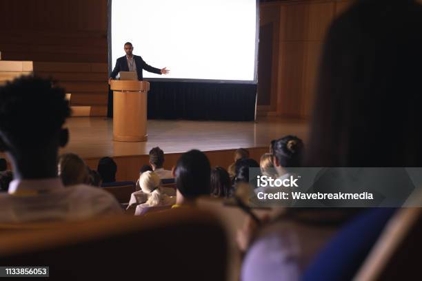 Businessman Giving Presentation On White Projector In Front Of The Audience Stock Photo - Download Image Now