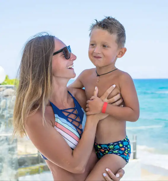 Photo of Smiling and happy mother and her son playing the beach. Concept of friendly family. Miami beach.