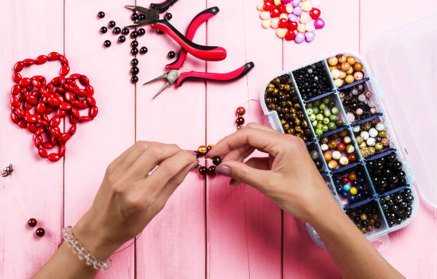 istock Jewelry making. Female hands with a tool on a pink 1133856518