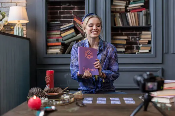 Photo of Nice positive woman holding a book on esoterics