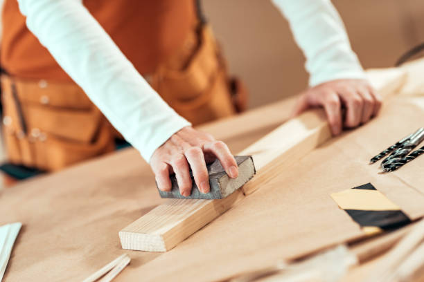 istock Female carpenter manually sanding wooden plank 1133859696