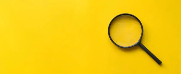 Photo of close up magnifier glass on yellow background for design on web page or wbesite concept