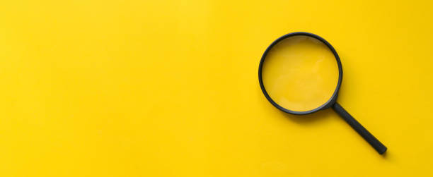 feche acima do vidro do magnifier no fundo amarelo para o projeto na página da web ou no conceito do wbesite - investigação assunto - fotografias e filmes do acervo