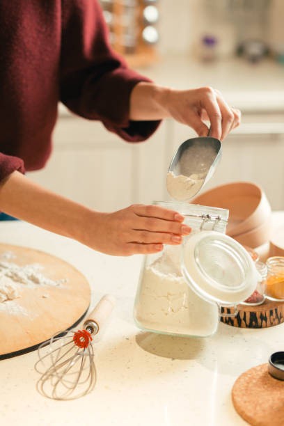 istock Woman holding glass jar and taking flour from it 1133863022