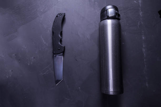 istock Knife and thermos. Black knife and shiny bottles. 1133863774