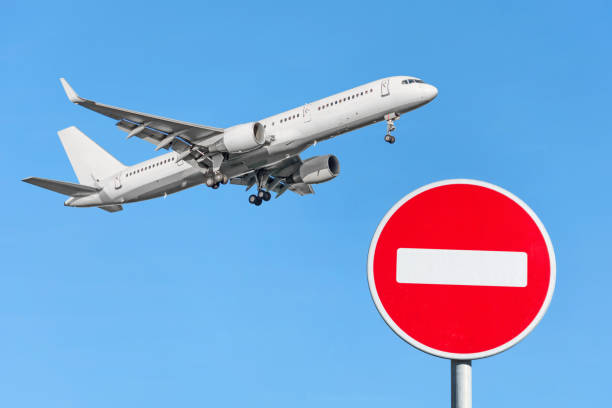 red brick stop sign and an airplane flying in the sky. flight ban concept - entering airplane imagens e fotografias de stock
