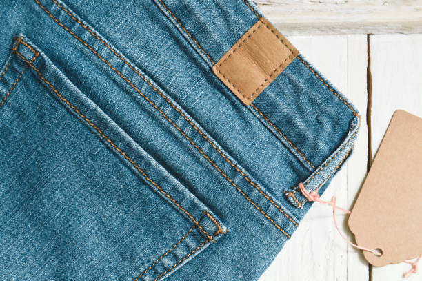 istock Old blue jeans with tag on white wooden background 1133868543