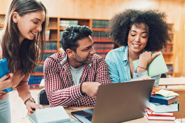 Multi-ethnic group of students studying together Different ethnicity students working together in the library community college stock pictures, royalty-free photos & images