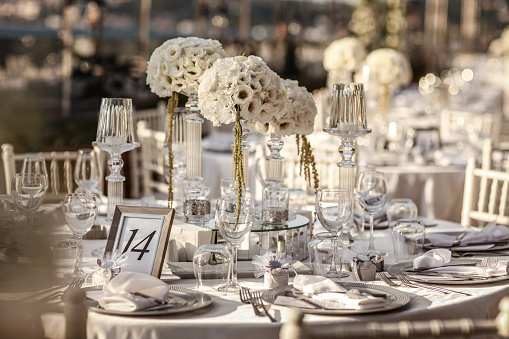 A closeup shot of a wedding reception table setting with white plates, candles and floral decorations