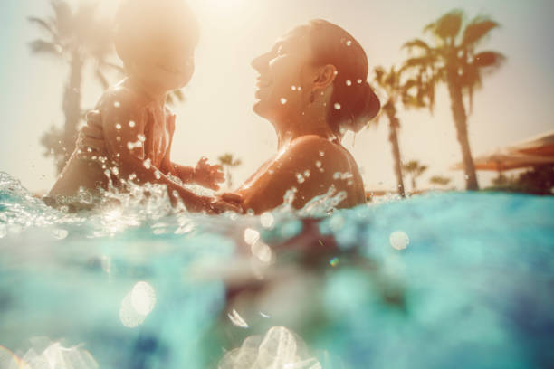 madre con niño divirtiéndose en piscina al atardecer - child beach playing sun fotografías e imágenes de stock