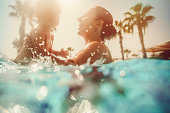 Mother with child having fun in pool at sunset
