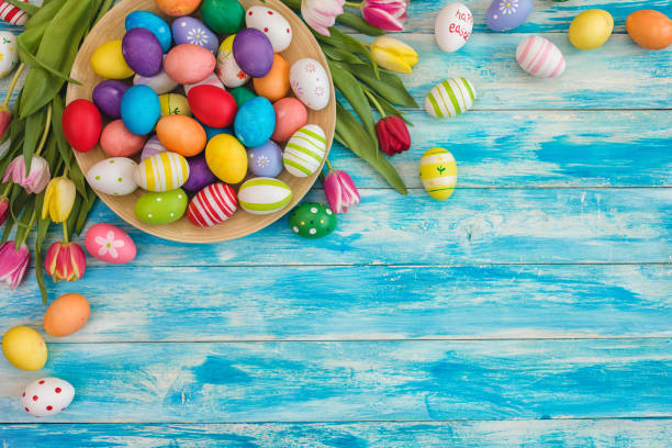 Easter background with painted eggs and colorful tulips, top-down composition