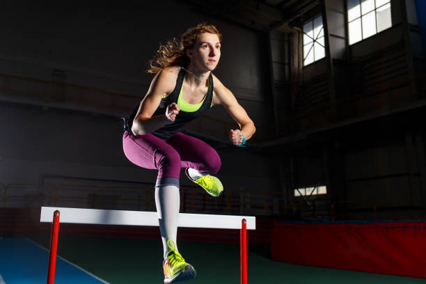 istock Young sportswoman running and jumping over hurdle 1133877462
