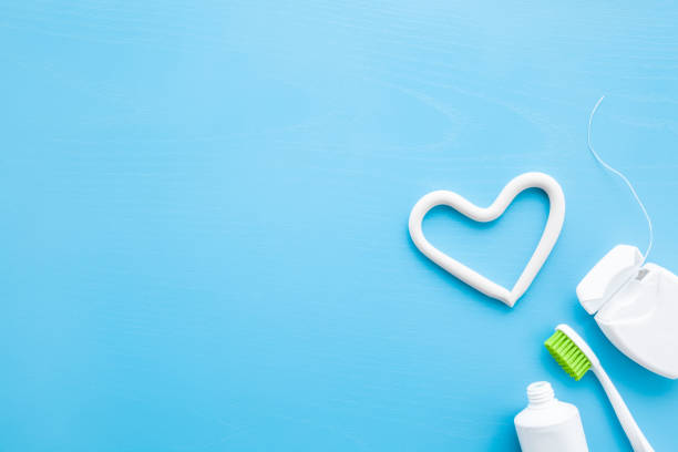 toothbrush, white tube of toothpaste, container of dental floss on pastel blue background. heart shape created from paste. love healthy teeth concept. empty place for text, quote, sayings or logo. - dental floss brushing teeth dental hygiene dental equipment imagens e fotografias de stock