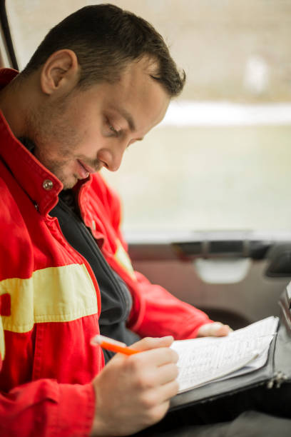 istock Young handsome paramedic in his ambulance smiling and writing notes. Looking at camera. 1133882114