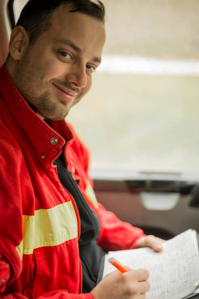 istock Young handsome paramedic in his ambulance smiling and writing notes. Looking at camera. 1133882176