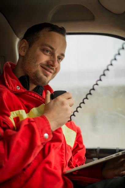 istock Young handsome paramedic in his ambulance smiling and talking to transmitter. 1133882240