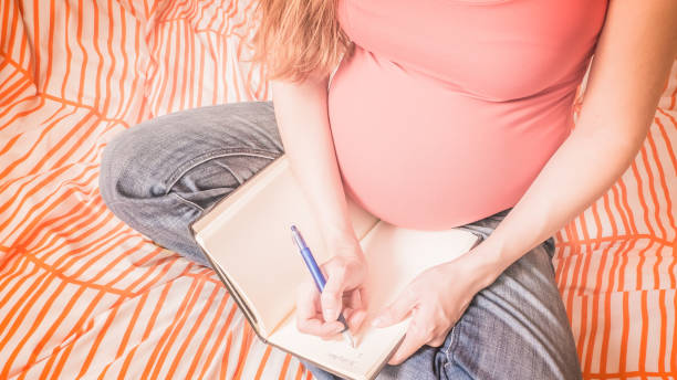 Pregnant woman is handwriting a birth plan at home