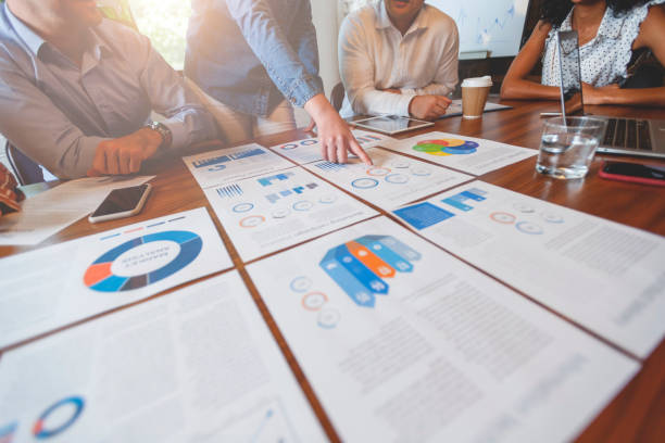 istock Paperwork and hands on a board room table at a business presentation or seminar. 1133887500